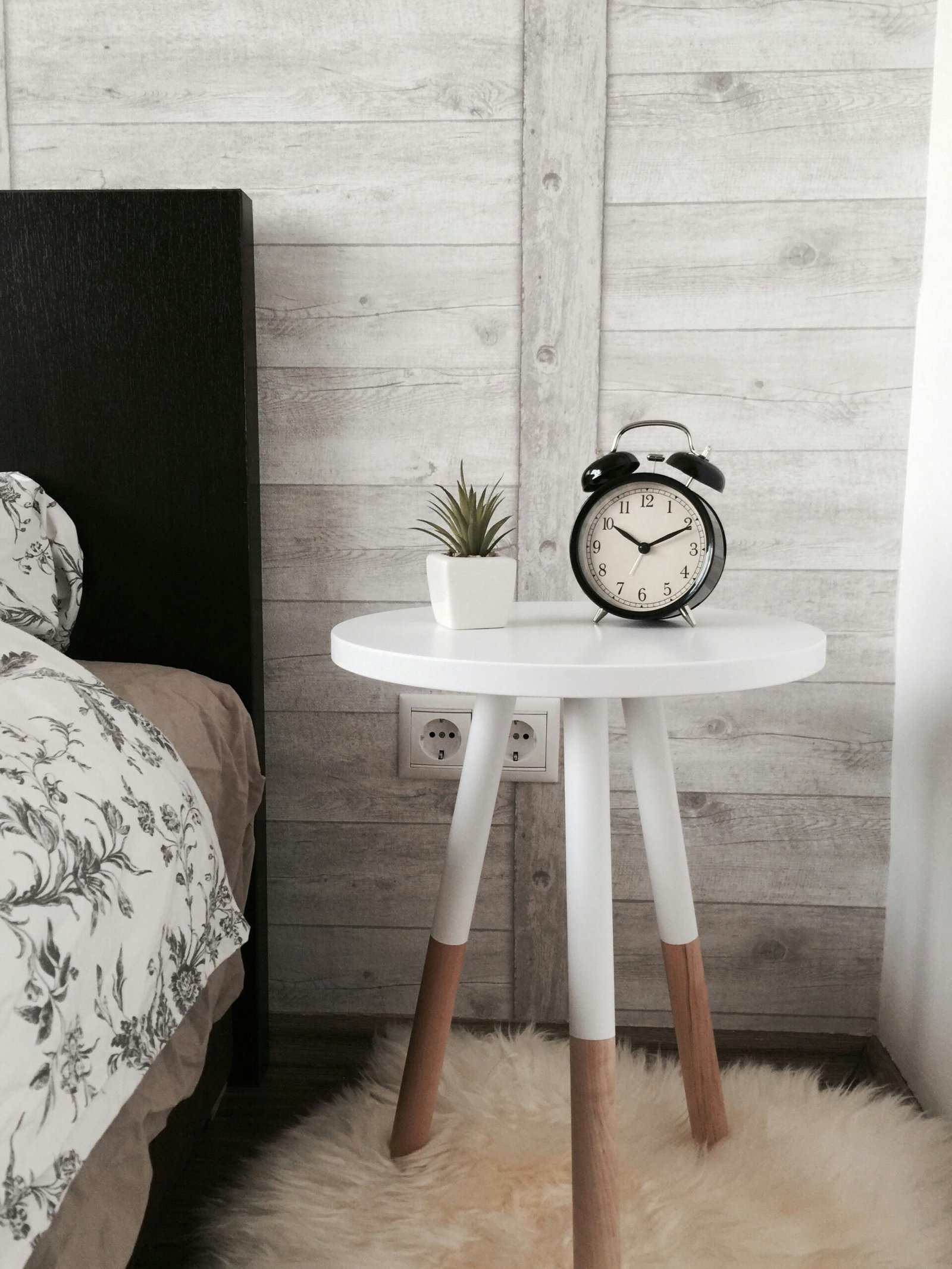 black alarm clock at black alarm clock at 10:10 on white wooden table near table