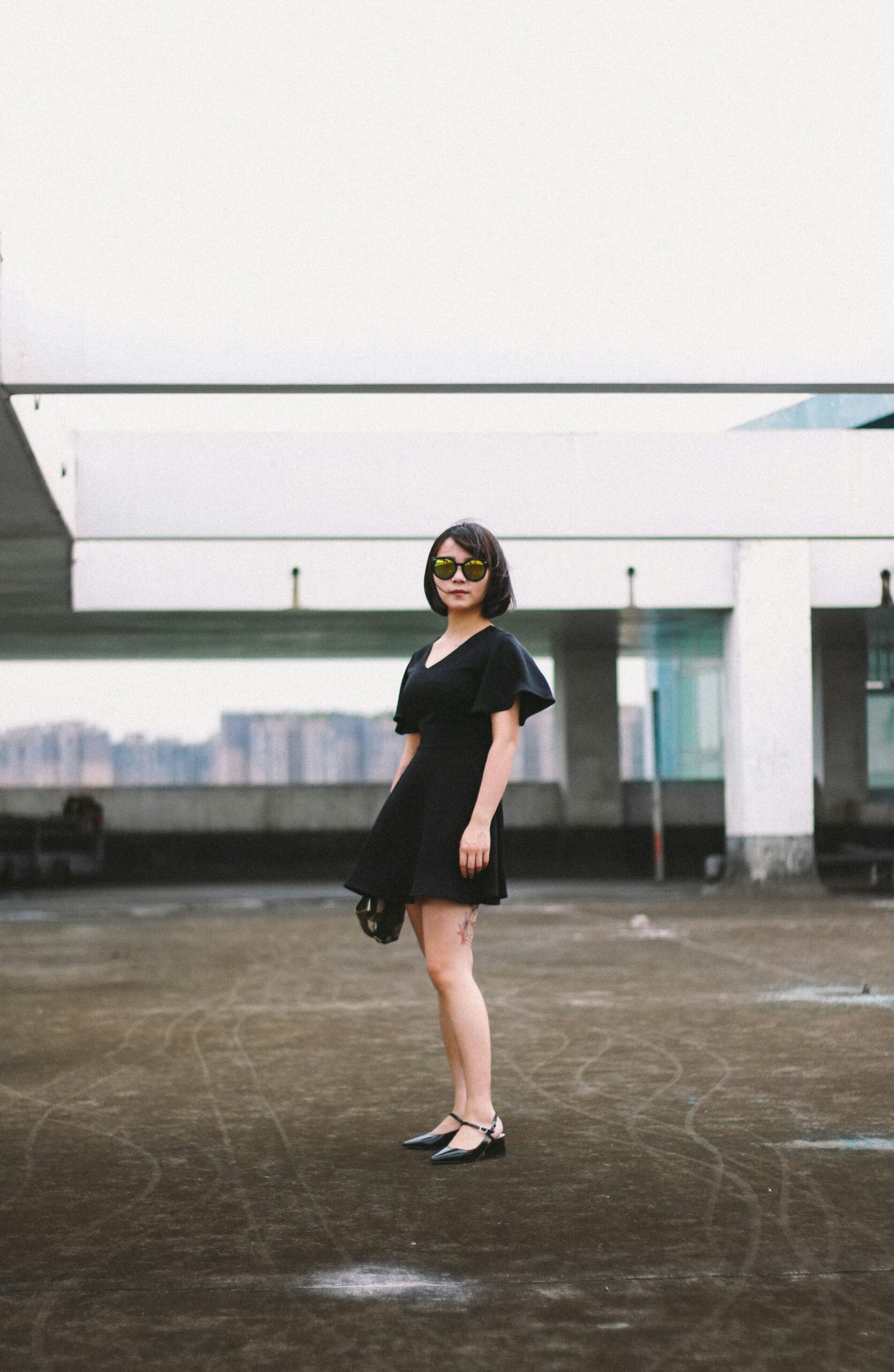 woman in black minidress woman in black minidress and black sunglasses standing on street